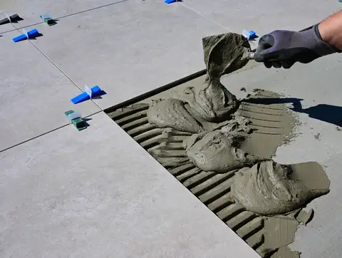 Gloved hand applying mortar during ceramic tile installation
